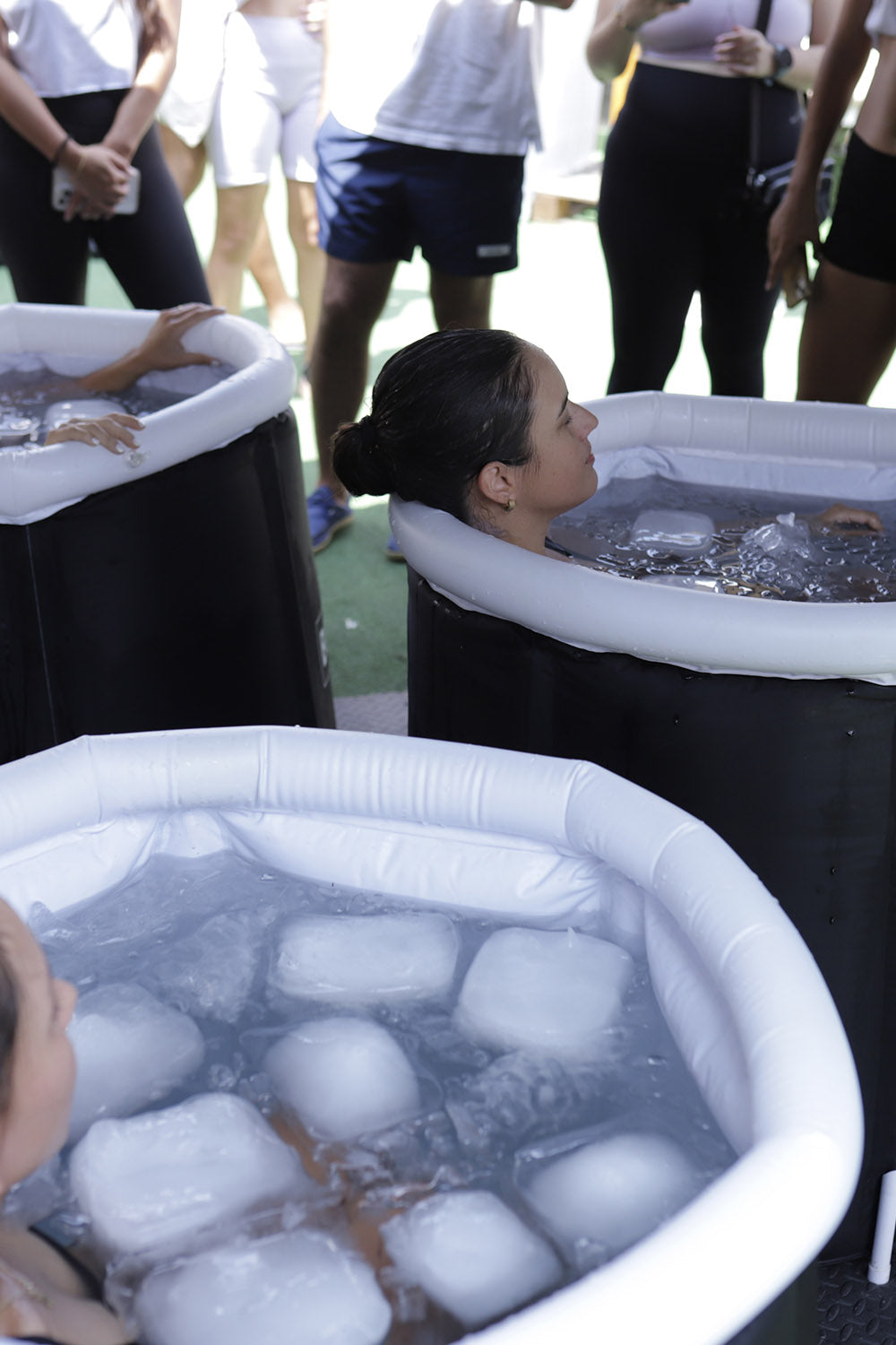 Tres bañeras portátiles con hielo con una persona dentro de cada una.